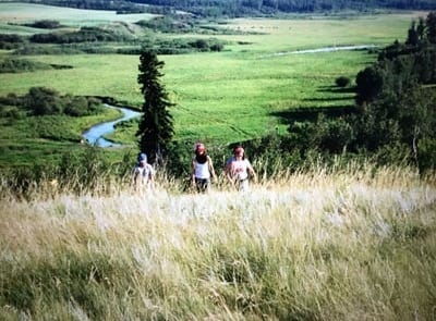 A family walks uphill through tall grass