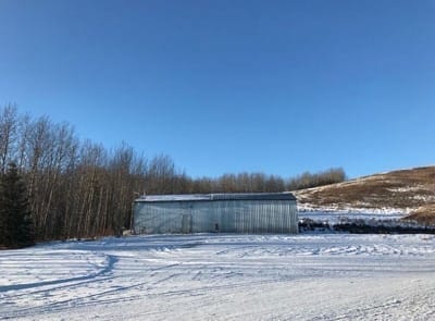 A snowy field with hills and forests in the background